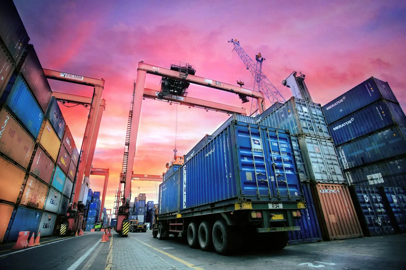 Container port with cranes and trucks at sunset