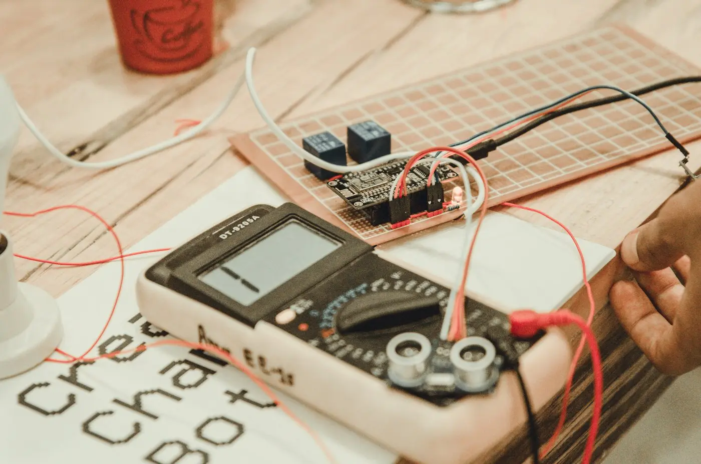 Hand holding a multimeter probing a circuit